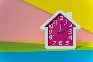 Pink House-Shaped Clock on Colorful Geometric Background