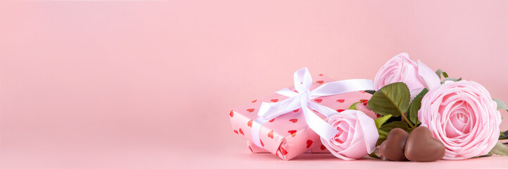 Valentine day, February 14 holiday background with pink roses flowers bouquet, gift boxes and heart-shaped chocolates on pastel colored pink background copy space