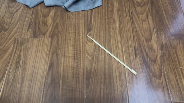 A wooden chopstick falling onto the laminate floor and knocking