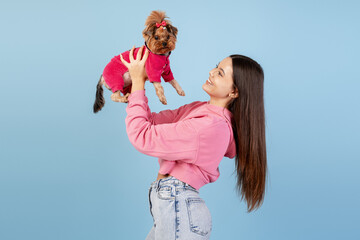 Young woman enjoying playtime with her adorable Yorkshire terrier pet