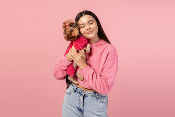 Young woman embracing and showing affection to a small Yorkshire terrier puppy