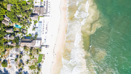 Tulum Beach, Quintana Roo, Mexico, Beach with a resort in the background. The water is calm and the sky is clear. The beach is full of people enjoying the day