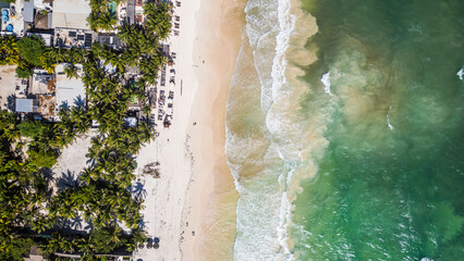 Tulum Beach, Quintana Roo, Mexico, Beach with palm trees and a green ocean. The beach is crowded with people and there are several boats in the water
