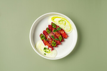 Brightly colored toppings create an artistic arrangement on a simple white plate. Fresh greens and smooth sauces add a touch of elegance, perfect for a culinary masterpiece