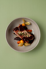 Tender beef fillet is beautifully arranged with a deep, flavorful sauce and garnished with colorful vegetables, creating an artistic culinary masterpiece