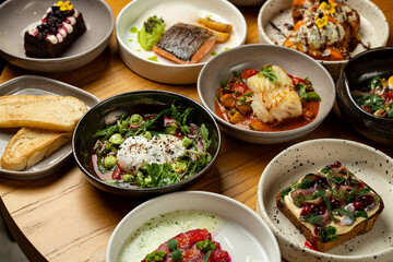 A delightful assortment of colorful dishes awaits on a wooden table, featuring fresh seafood, vibrant salads, and a tempting dessert, perfect for a sunny lunch outing
