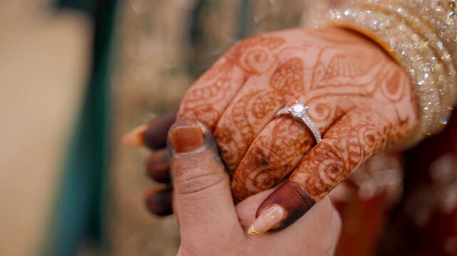 Groom is holding a brides henna painted hand with the ENGAGEMENT ring. Ttraditional Indian clothes, Elements of hindu wedding. 