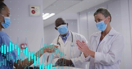 Handing nurse in blue scrubs offering device to doctor in clinic corridor, white coat, data overlay