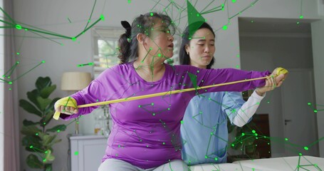 Stretching patient in purple top gray pants on sofa at home, medical therapist guiding yellow band
