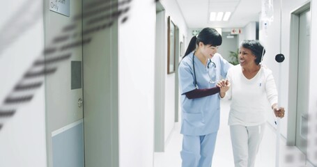 Walking nurse in scrubs holding patient down hospital hall with IV pole and stethoscope, copy space