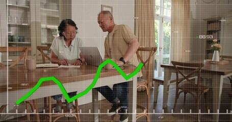 Mature man tapping laptop and pointing green graph overlay rising as couple reviewing finances - Powered by Adobe