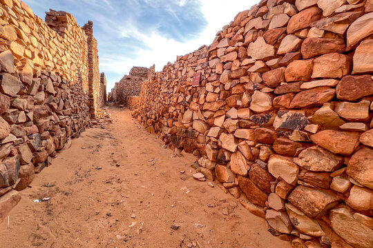 Ouadane in Mauritania. A view of a narrow street in the town between the stone walls of ruined buildings.