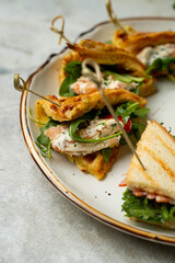 This scene showcases a beautifully arranged platter of savory sandwiches and bites, featuring grilled bread, creamy fillings, and crisp greens. A delightful treat for any gathering