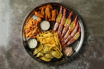 A vibrant platter showcases an assortment of fried seafood, including golden shrimp and crispy fish, complemented by tasty sauces and golden fries. Perfect for a sharing experience