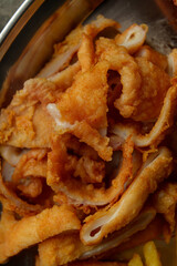 Deliciously golden fried fish fillets piled high on a tray, accompanied by crispy fries. A mouthwatering dish ideal for enjoying by the beach in warm weather
