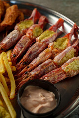 Succulent shrimp stuffed with flavorful ingredients rest on a gleaming platter next to crispy fries and a rich dipping sauce, all inviting and mouthwatering