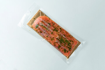 Fresh salmon fillet adorned with herbs rests inside stylish packaging, awaiting creative culinary exploration in a cozy home kitchen setting, perfect for a delightful meal