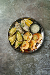 A vibrant seafood platter showcases grilled oysters and scallops garnished with fresh herbs. Served with a tangy dipping sauce, this dish invites savoring the flavors of the ocean