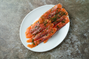 Succulent salmon fillets lie elegantly on a white plate, adorned with vibrant green herbs. The scene evokes a sense of freshness and culinary delight