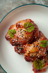 Tender chicken wings glisten with a sweet and spicy glaze, sprinkled with sesame seeds. Fresh green herbs add a pop of color for a delightful dish served on a rustic plate