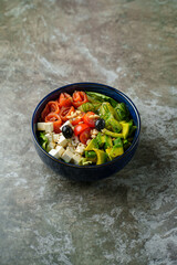 Brightly colored veggies, olives, and feta cheese combine in a rustic blue bowl. This delightful mix invites a healthy, vibrant meal, perfect for lunchtime enjoyment