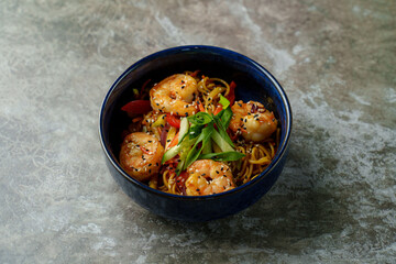 A delightful bowl of shrimp and noodles showcases vibrant colors with red peppers and green onions. The dish sparkles with sesame seeds, inviting an enticing culinary experience