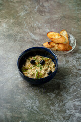 Warm creamy mushroom soup fills a deep blue bowl, garnished with fresh herbs and olives, paired with crispy toasted bread on a delicate glass plate, creating a cozy dining experience