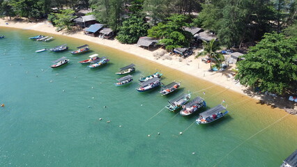 Drone image of beach with anchored boats, fishing village, forest, and construction site near shore. © Na'im