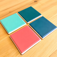 Fototapeta premium Colorful ceramic coasters in mint green, teal, navy blue, and coral arranged on a wooden table