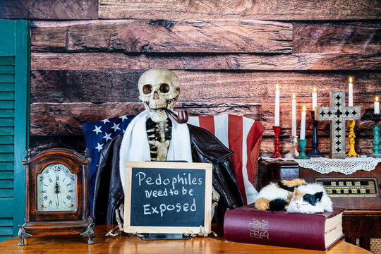 skeleton smoking pipe holding sign pedophiles need to be exposed