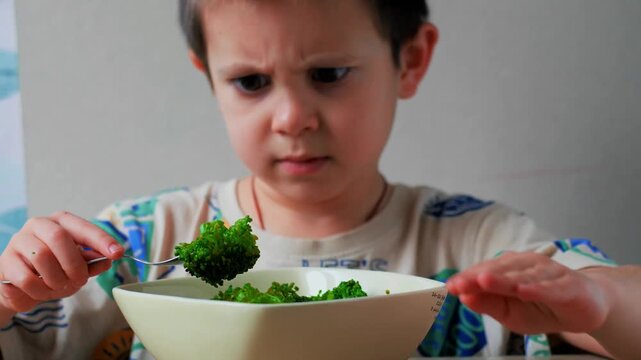 Little boy refusing broccoli &ndash; child rejecting healthy food and making a disgusted face