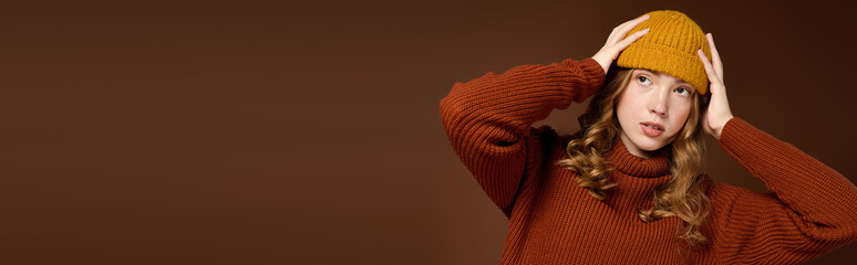 Redhead young woman showcases winter fashion with style in a cozy studio setting