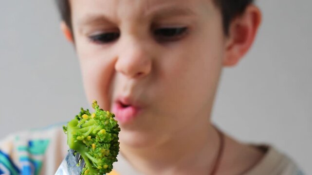 Young Boy Showing Disgust and Refusing to Eat a Piece of Fresh Broccoli - Child with Funny Disgusted Face Looking at Vegetables, Picky Eater Concept