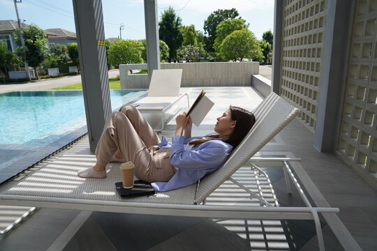 Young woman reading book and relaxing on sunbed outdoor