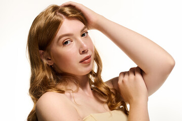 Fototapeta premium Stunning redhead woman poses gracefully in a bright studio setting