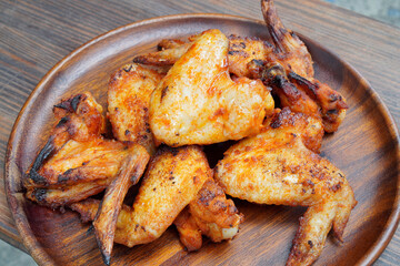 Crispy grilled chicken wings are arranged on an old wooden tray.