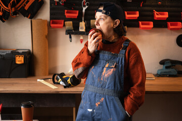 repairwoman or female mechanic eating food in her repair shop or garage