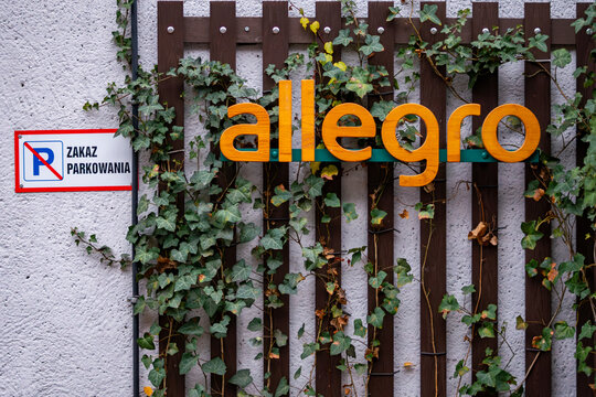 Wooden allegro sign mounted on fence covered with ivy next to no parking sign outdoors