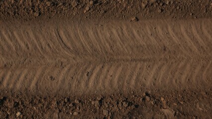 Close-up of a dirt road with tire tracks and a textured surface, showing the pattern created by vehicle passage.