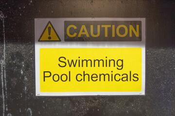 A yellow CAUTION Swimming Pool chemicals sign