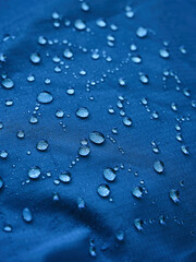 Water drops on waterproof membrane fabric. Detail view of texture of blue waterproof cloth.