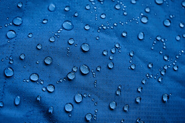 Water drops on waterproof membrane fabric. Detail view of texture of blue waterproof cloth.