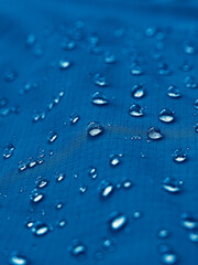 Water drops on waterproof membrane fabric. Detail view of texture of blue waterproof cloth.