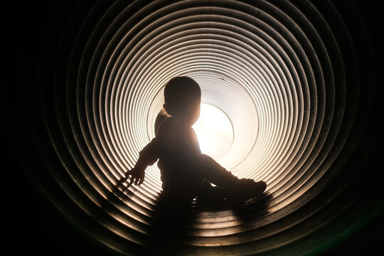 Child playing in corrugated plastic park tunnel