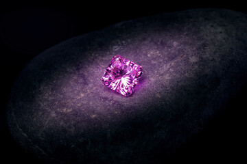 A small pink diamond is sitting on a rock