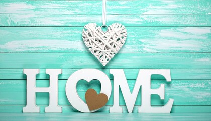 Large White "HOME" Letters with Heart Cutout Hanging on Rustic Mint Green Wooden Wall with Woven Heart