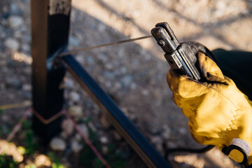 Close-up of the hands of a male welder, wearing protective gloves, working at a welding machine.