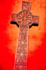 Celtic cross carved in stone on a red background