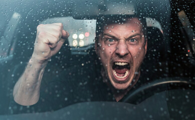 Conducteur en col&egrave;re hurlant et levant le poing &agrave; travers un pare-brise sous la pluie