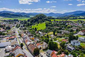 Naklejka premium Aerial drone view of Jesenik town in Czech Republic showcasing the central market square and historic buildings nestled in Jeseniky Mountains, panoramic urban landscape in sunny summer day